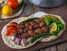 kött tikka tallrik eras i en maträtt sida se på trä- tabell bakgrund foto