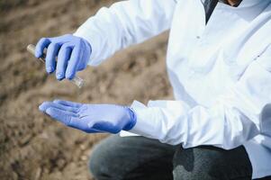 jord testning. agronomi specialist tar jord prov för fertilitet analys. händer i handskar stänga upp. miljö- skydd, organisk jord certifiering, fält arbete, forskning. foto