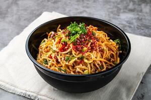 bashu kall spaghetti garnering med chili klistra, vår lök och sesam frön eras i skål isolerat på trä- tabell sida se av hong kong snabb mat foto