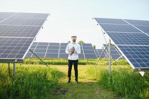 positiv skäggig manlig investerare stående mot solceller paneler producerar alternativ energi. foto