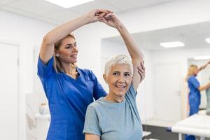 fysioterapeut kvinna ger övning med hantel behandling handla om ärm och axel av senior kvinna patient fysisk terapi begrepp foto