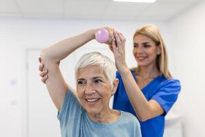 professionell terapeuter är stretching muskler, senior patient med onormal muskulös symtom, fysisk rehabilitering terapier och behandling av fysiologisk störningar förbi sjukgymnaster begrepp. foto