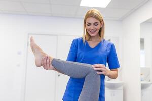 fysioterapeut arbetssätt med patient i klinik, närbild. en modern rehabilitering fysioterapi arbetstagare med senior klient, fysisk terapeut stretching patient knä foto