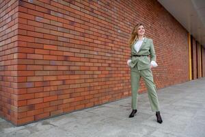 porträtt av en framgångsrik företag kvinna i främre av modern företag byggnad. ung chef poser utanför. kvinna företag ledare. foto