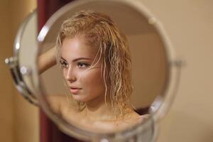 sexig blond flicka med våt hår efter bad loks i de spegel foto