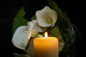 brinnande vax ljus i stänga upp och vit calla lilja foto