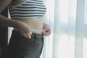 kvinnor kropp fett mage. fet kvinna hand innehav överdriven mage fett. diet livsstil begrepp till minska mage och form upp friska mage muskel. foto