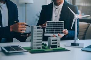 två ung ingenjörer expertis i sol- cell installation möten och diskussion i de jobb. planera till Installera sol- solceller paneler på tak topp i de kontor rum med fabrik byggnad planen. foto