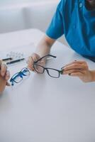 närbild av asiatisk kvinna läkare talande med äldre patient som visar eyeball modell och förklara öga sjukdom i sjukhus foto