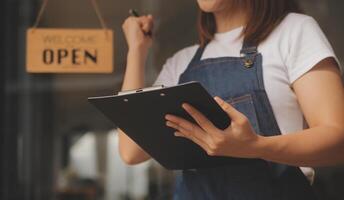 uppstart framgångsrik småföretagare SM skönhet flicka stå med surfplatta smartphone i kafé restaurang. porträtt av asiatisk solbränna kvinna barista café ägare. sme entreprenör säljare affärsidé foto