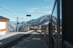 se från tåg löpning till station bland swiss alps på schweiz foto