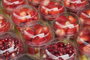 mogen röd jordgubbar i. plast behållare försäljning på affär foto