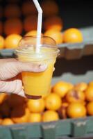 kvinnor innehav en flaska av orange juice mot mot frukt bakgrund foto