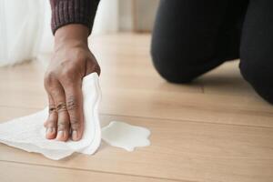 hand avtorkning spillts mjölk med papper servett på golv , foto