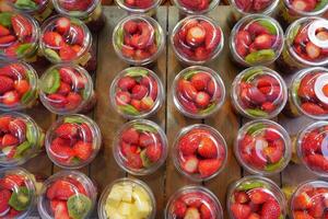 mogen röd jordgubbar i. plast behållare försäljning på affär foto