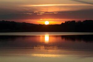 ai genererad gyllene solnedgång speglar på lugn sjö, gjutning fascinerande glöd foto