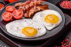 engelsk frukost med stekt ägg, bacon, bönor, tomater, kryddor och örter foto