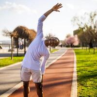 ung afrikan-amerikan man är utövar i de stad. han är stretching hans kropp. foto