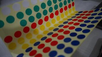 en ark av fyrkant klistermärken med en färgrik polka punkt design. de klistermärken är anordnad i en rad på en klar plast ark. de bakgrund är gul. foto