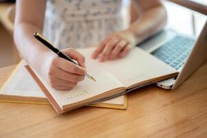 en närbild bild av en kvinna innehav en penna, skrivning något i en anteckningsbok eller förvaring dagbok. foto