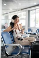 en kvinna passagerare Sammanträde på en väntar sittplats i de flygplats terminal, väntar för henne ombordstigning ringa upp. foto