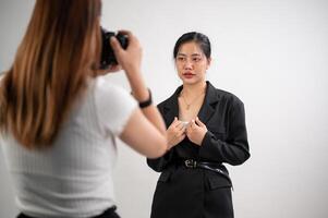 ett attraktiv ung asiatisk kvinna modell är Framställ för en fotograf, tar en fotografering i en studio foto