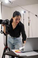 Häftigt, professionell asiatisk kvinna fotograf är kontroll bilder på henne bärbar dator, arbetssätt i de studio foto