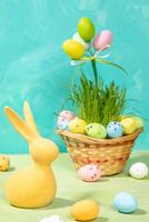 Semester påsk fortfarande liv med gul dekorativ kanin och ägg på turkos. vertikal formatera. foto