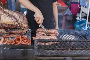 person grillning kött på en rustik grill i Mexiko. gata bås av grillad kött. foto