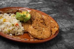 panerad friterad fisk och ris i en lera maträtt på en trä- tabell. foto