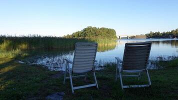 två plast stolar förbi de sjö på en sommar eftermiddag foto