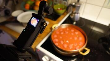 en digital kamera är filmning hemlagad köttbullar sjuder i tomat sås foto