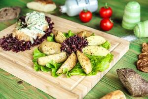 trä- skärande styrelse med sallad och potatisar foto