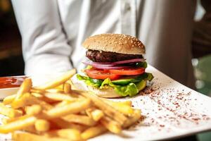 burger och franska frites på bricka foto