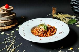 tallrik av spaghetti med tomat sås på svart tabell foto