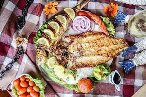 tallrik av grillad fisk och grönsaker på en picknick filt foto