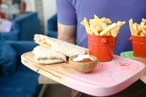 person innehav bricka med franska frites och smörgås foto