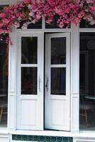 byggnad fixtur vit dörr Utsmyckad med rosa blommor foto