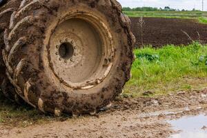 smutsig dubbel- hjul av en stor lantbruk traktor på smuts väg på sommar dag foto