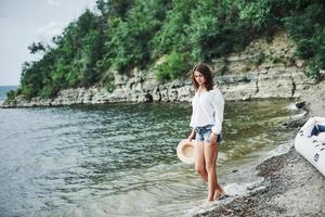 vatten tar bort alla besvär. underbar modell flicka poserar på stranden med klippa bakgrund med träd