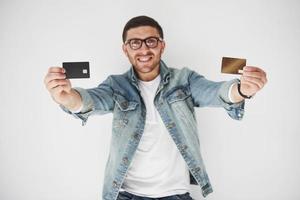 ung stilig manlig företagsledare i ledig klädsel med ett kreditkort i fickorna på en vit bakgrund. konceptet med handel på internet och lättheten med elektroniska pengar foto