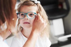 läkare som ger barnet nya glasögon för hennes syn foto