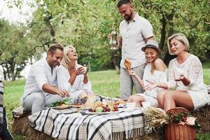 glad skratt. grupp av vuxna vänner har en vila och konversation på bakgården av restaurang vid middagstid foto