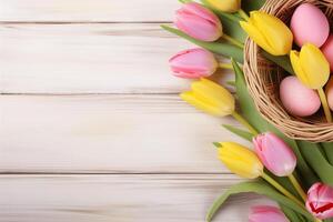 påsk Semester firande baner hälsning kort baner med rosa målad ägg i fågel bo korg och gul tulpan blommor på vit trä- bakgrund tabel textur. foto