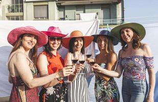 grupp av kvinna vänner bär hattar toasting röd vin foto