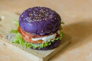stänga upp Foto av en hemlagad lila burger placerad på en keramisk tabell