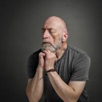 senior man med stängd ögon mediterar eller bön- foto