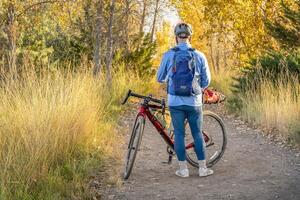 senior manlig cyklist med en touring grus cykel på en spår i nordlig colorado i falla landskap foto