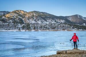 manlig vandrare med vandring poler på en Strand av frysta hästtand reservoar nära fort collins, colorado - vinter- vandring begrepp foto