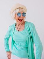 senior snygg glad kvinna i blå solglasögon och turkosa kläder. sommar, resor, anti ålder, glädje, pension, frihet koncept